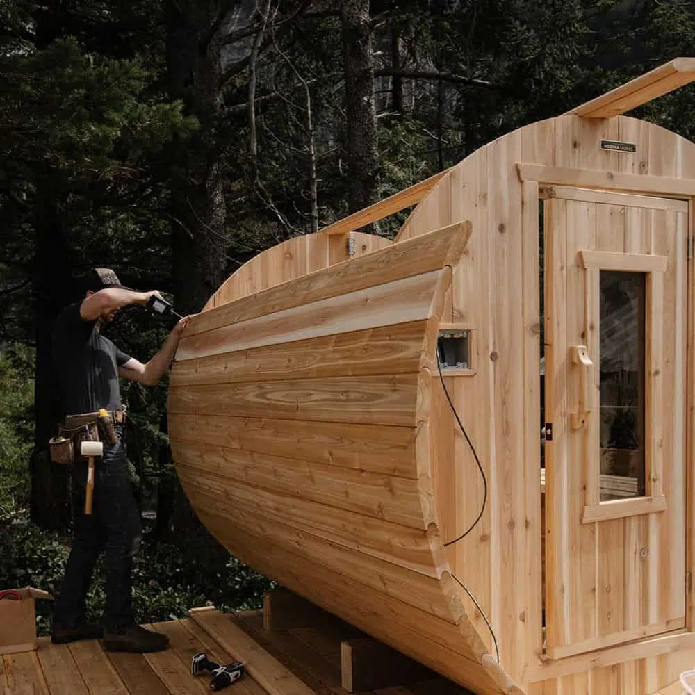 Man showing how to build a barrel sauna